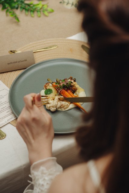 A guest eating a plated clean label dish of roasted cauliflower and carrots at a Slice catering event